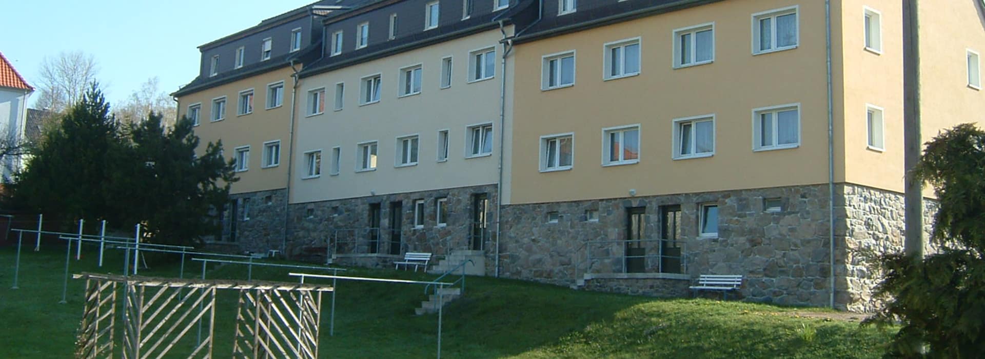 Hinterhof von Mehrfamilienhäusern mit Wäschestangen auf Grünfläche sowie Sonnenschein