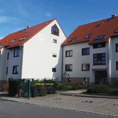 Weiße Wohnobjekte am Tauschaer Weg mit rotem Dach und Parkplätzen davor