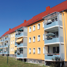 Fassade eines gelben Mehrfamilienhauses mit Balkonen und blauem Himmel